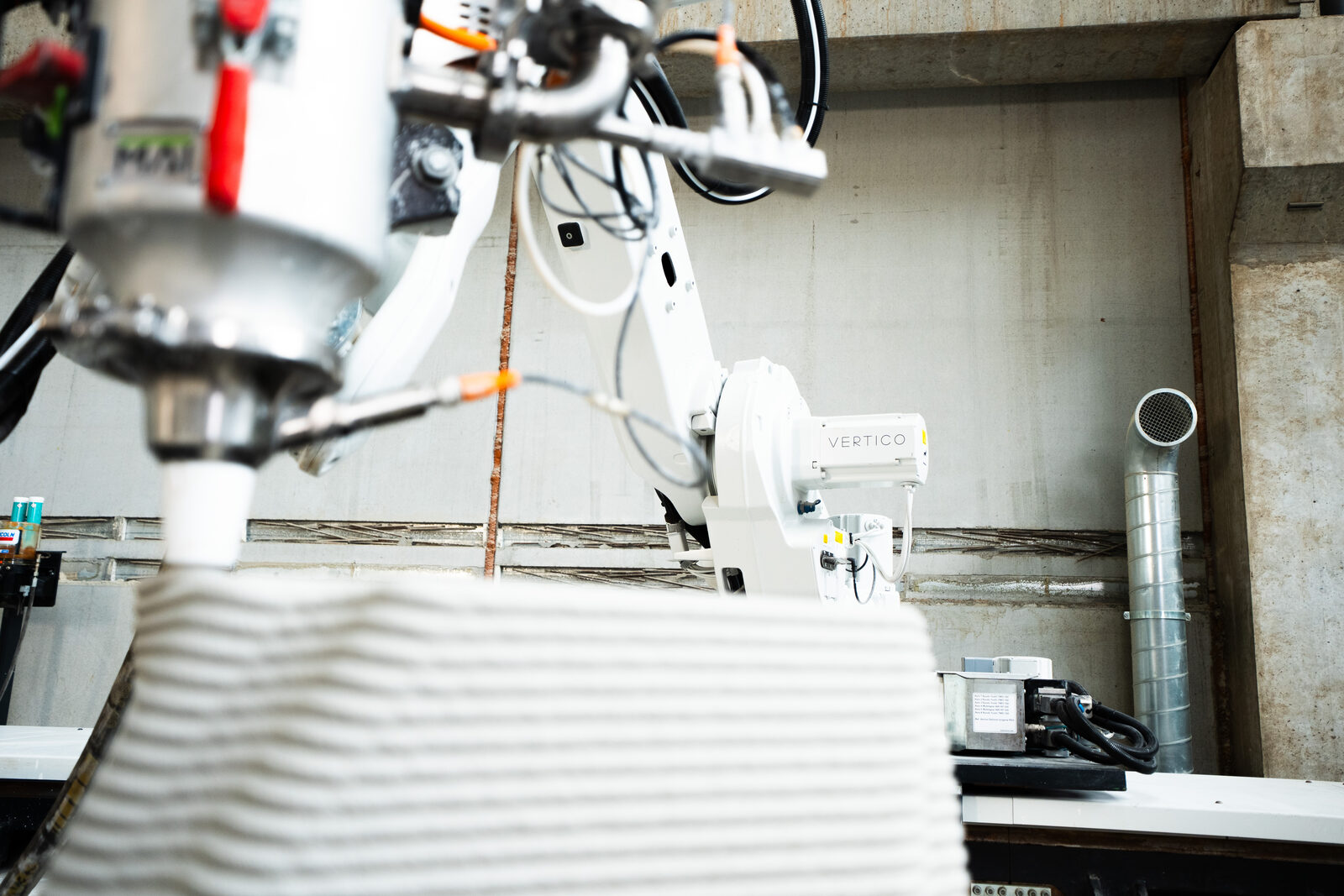 Seitlicher Blick auf Düse und Strang, dahinter der Roboterarm