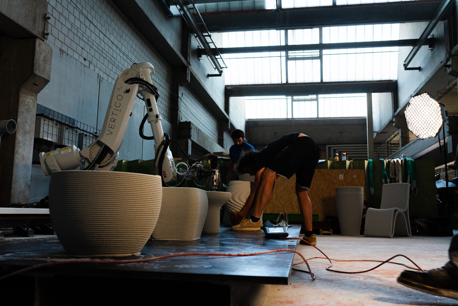 Gedruckte Schalen auf dem Druckbett, dahinter der Roboter in der Halle