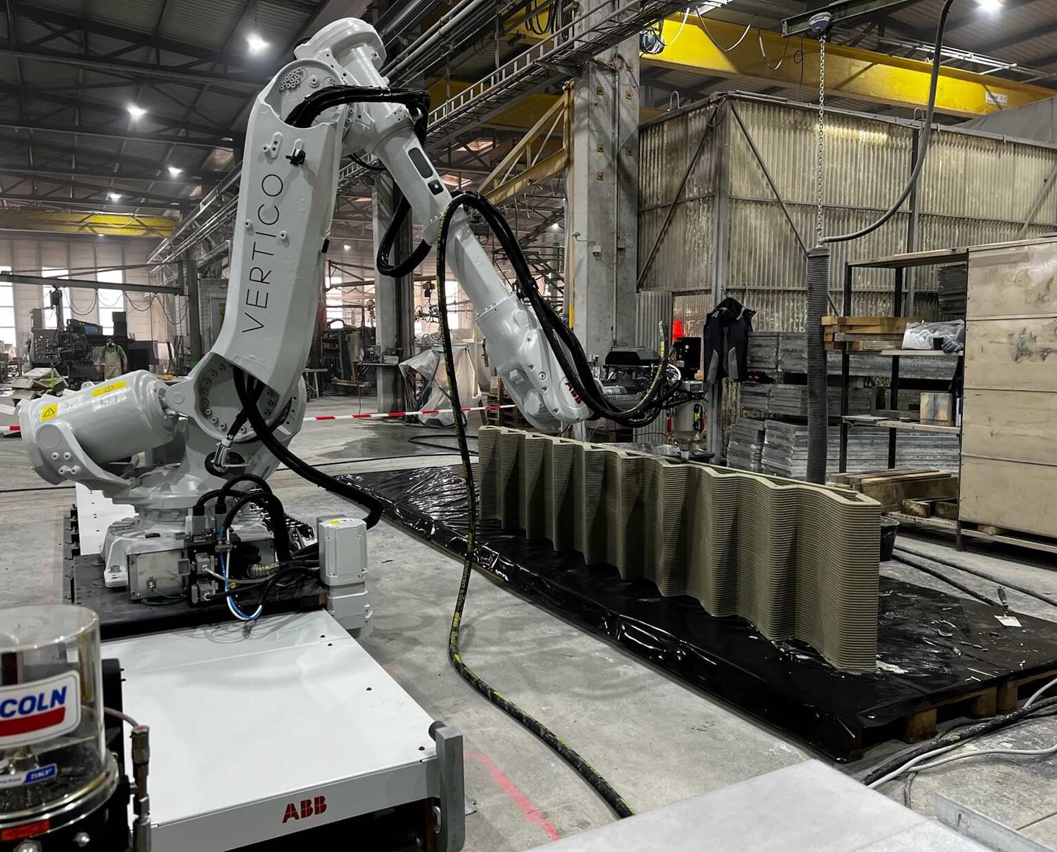 Roboterarm druckt ein Treppenelement in einer Werkhalle